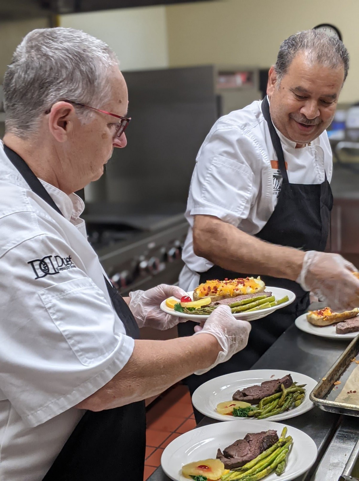 Chefs plating dishes in a restaurant kitchen.
