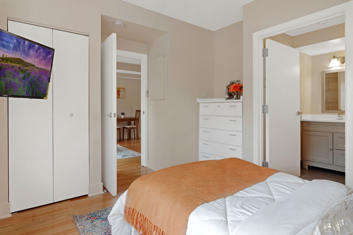 A cozy and modern bedroom with a neatly made bed, a white dresser, and neutral decor.