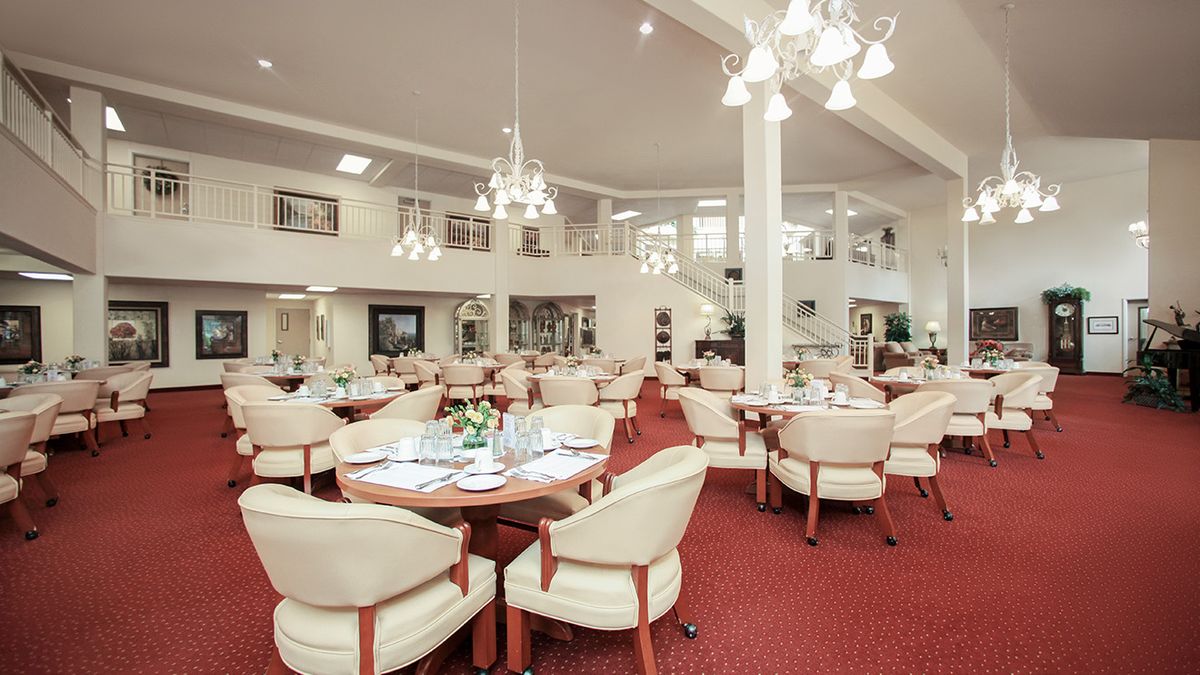 A spacious dining room with elegant chandeliers and neatly arranged tables and chairs.