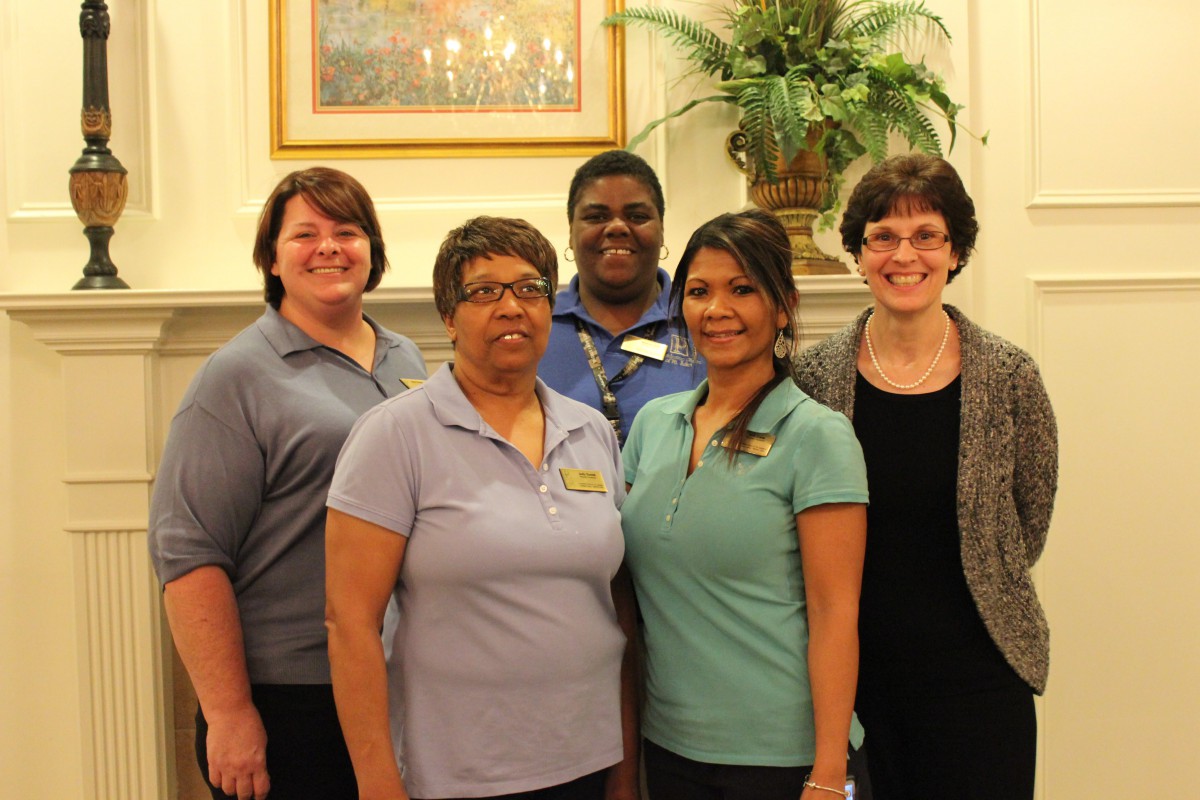 A group of five people smiling indoors.