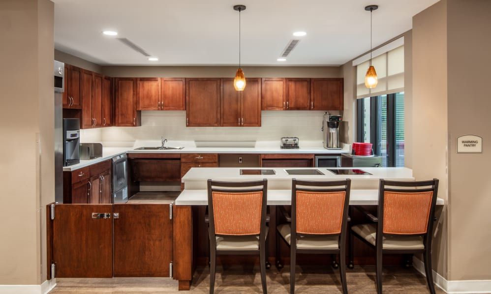 A modern kitchen with wooden cabinets and an island featuring bar stools and pendant lighting.