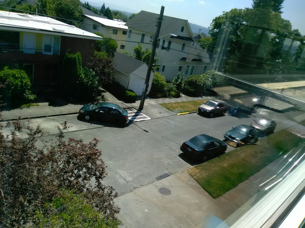A sunny residential street with parked cars and houses.