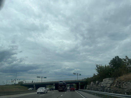 A view of a highway under a cloudy sky, with vehicles traveling and an overpass visible.