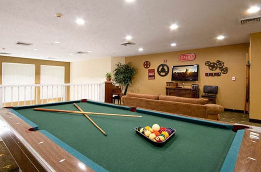 A cozy game room featuring a green-felt pool table and comfortable seating.
