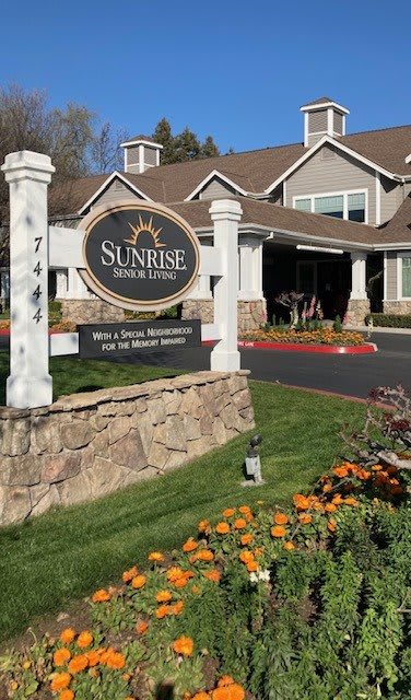 The entrance to a senior living community with landscaped gardens.