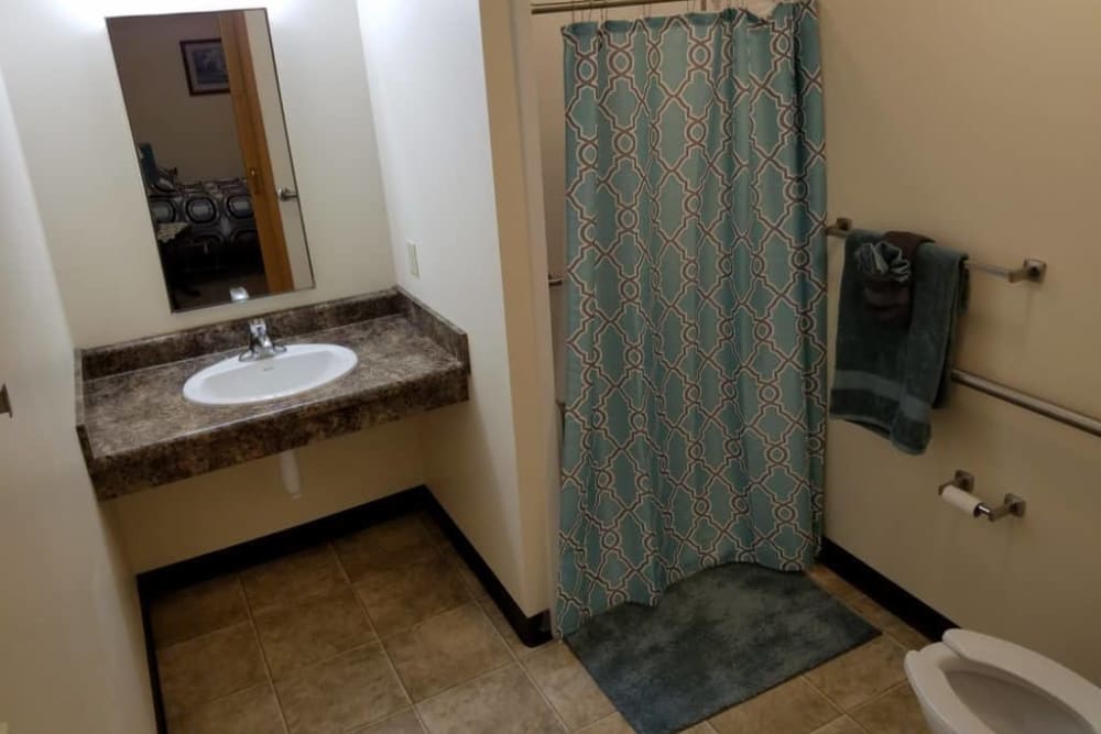 A bathroom with a sink, mirror, and shower area.
