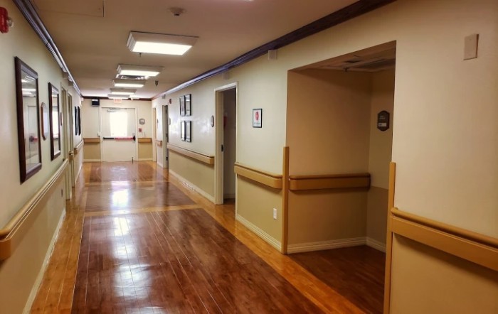 A clean and well-lit hallway with wooden floors and doorways on each side.