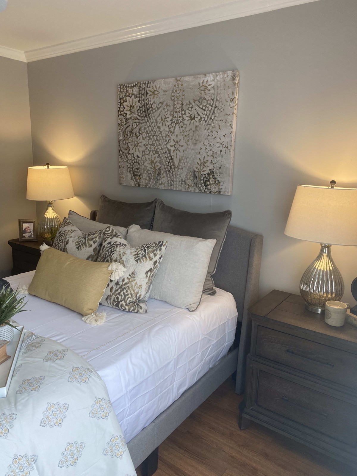 A cozy bedroom with a stylish decor featuring lamps, pillows, and wall art.