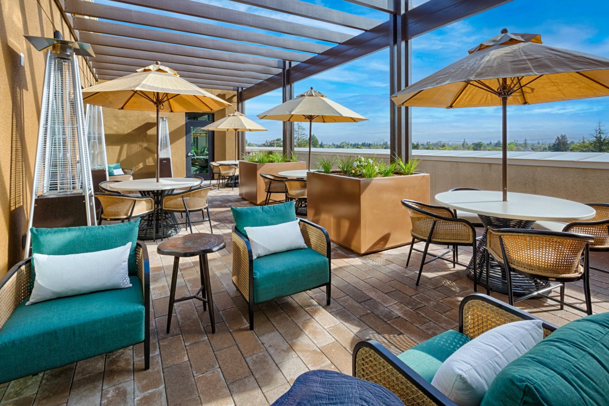 A stylish outdoor patio area with comfortable seating and umbrellas on a sunny day.