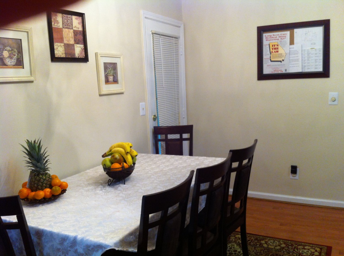A cozy dining room with a table set with a fruit bowl and framed artwork on the walls.