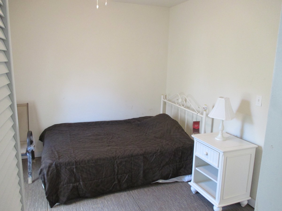 A minimalist bedroom with a bed and white nightstand.