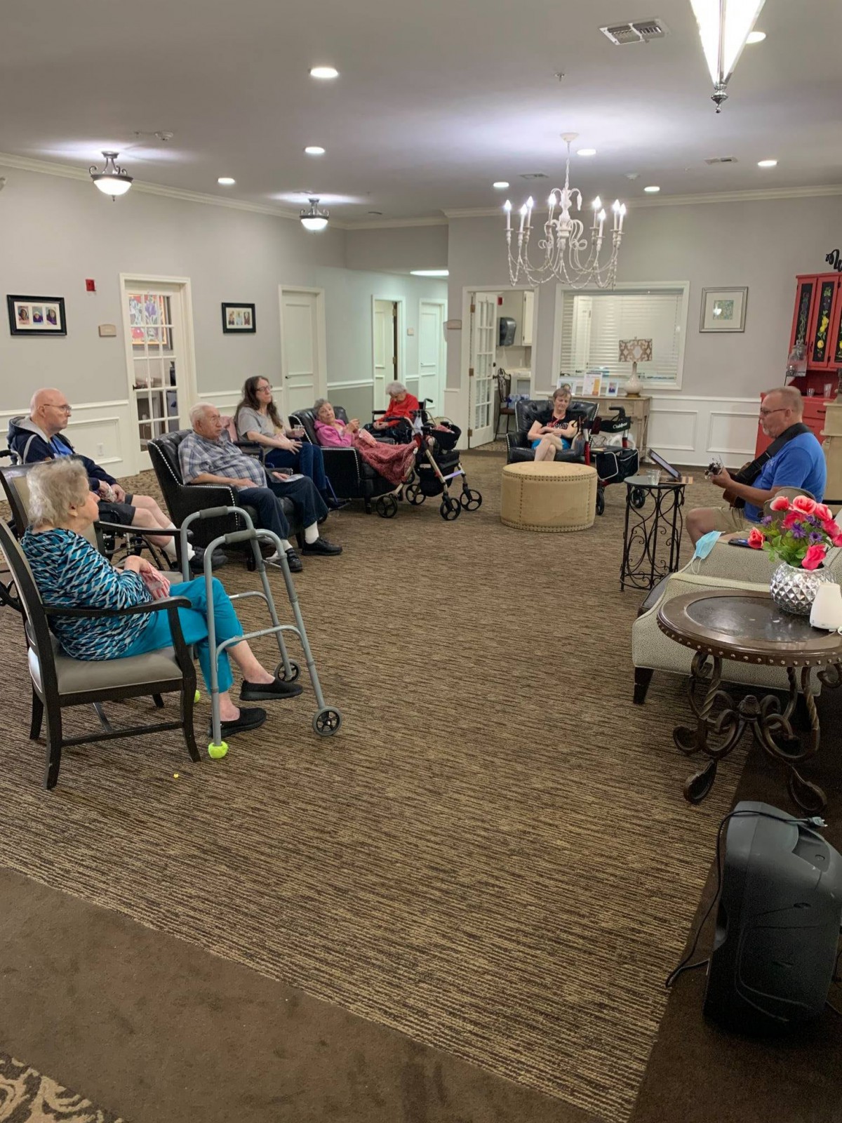 A group of elderly individuals gathered in a nursing home common area.