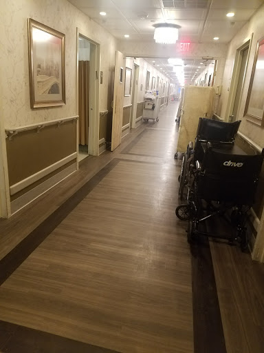 A quiet hallway in a healthcare facility, featuring wheelchairs alongside the walls.