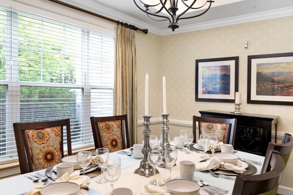 A beautifully set dining table with elegant candlesticks and a chandelier overhead.