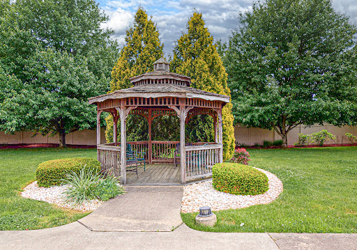 A charming gazebo nestled in a lush garden, surrounded by vibrant greenery and a serene pathway.
