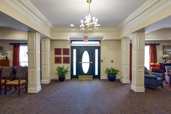 A well-decorated lobby with a chandelier and plants on either side of the entrance.