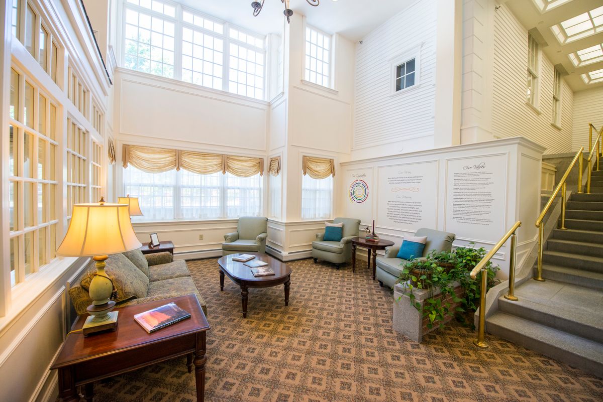 A spacious living room with high ceilings, large windows, and cozy furnishings.