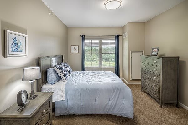 Cozy bedroom with a neatly made bed and large window.