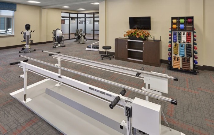A well-equipped rehabilitation center featuring parallel bars and various exercise equipment.