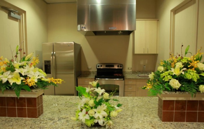 A modern kitchen featuring a granite countertop adorned with floral arrangements and stainless steel appliances.