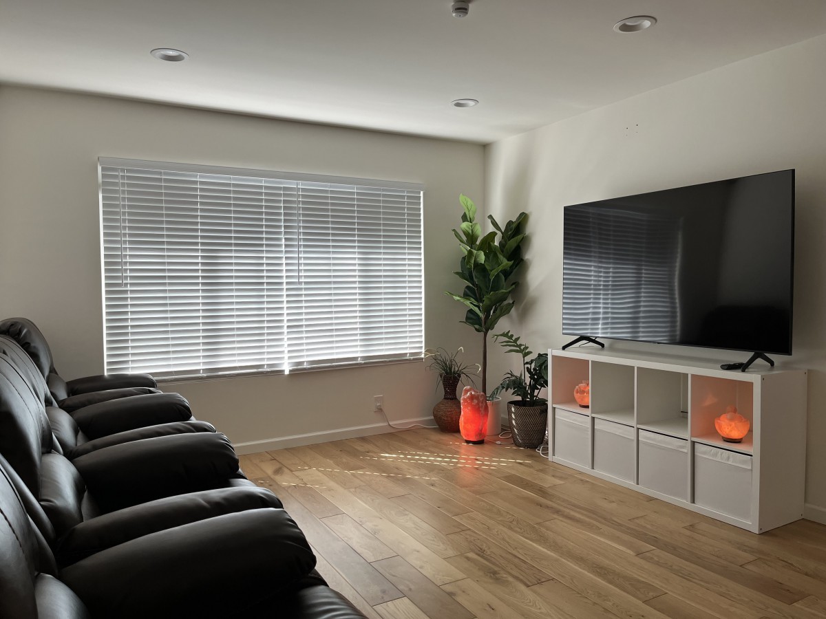 A modern, minimalist living room with a large TV, comfortable seating, and stylish decor.