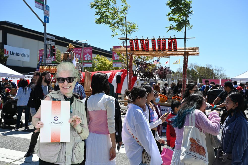 A lively outdoor festival with people in traditional clothing, surrounded by market stalls and decorations.