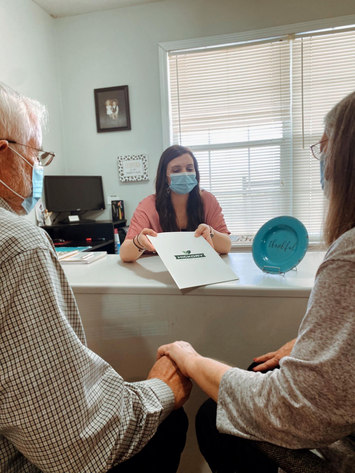 A couple meets with a consultant in an office setting, discussing a document.