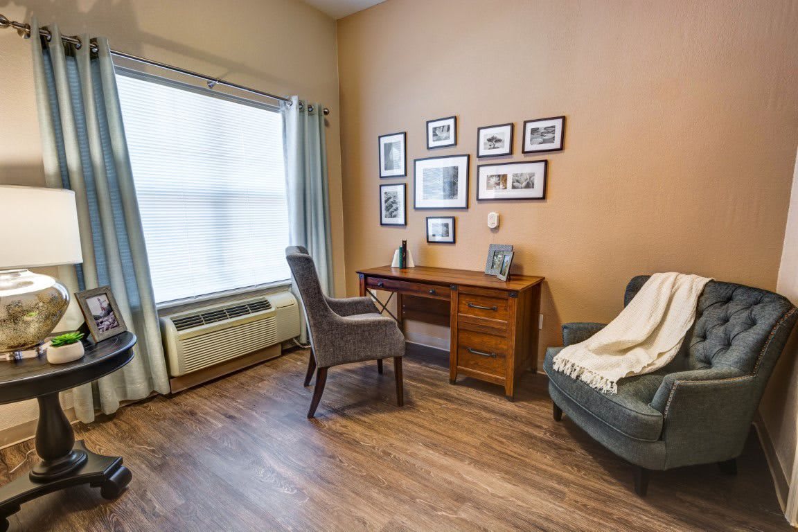 A cozy office space with a desk, chair, and artwork on the wall.