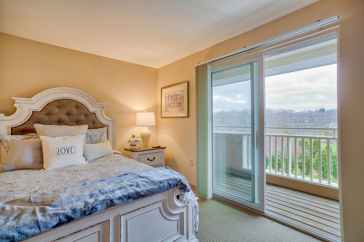 A cozy bedroom with elegant decor and a view of the balcony through sliding glass doors.