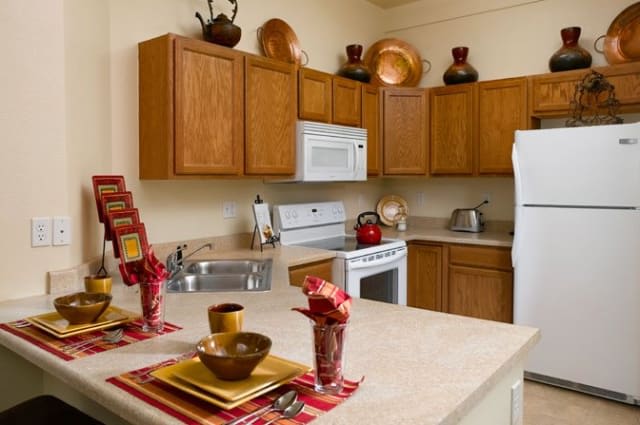 A cozy kitchen featuring wooden cabinets, modern appliances, and a neatly set dining area.