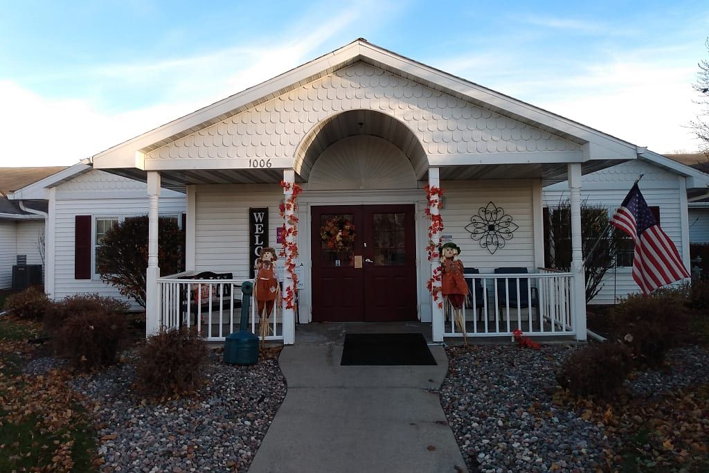 A white house with a decorated entrance and porch, featuring holiday ornaments.