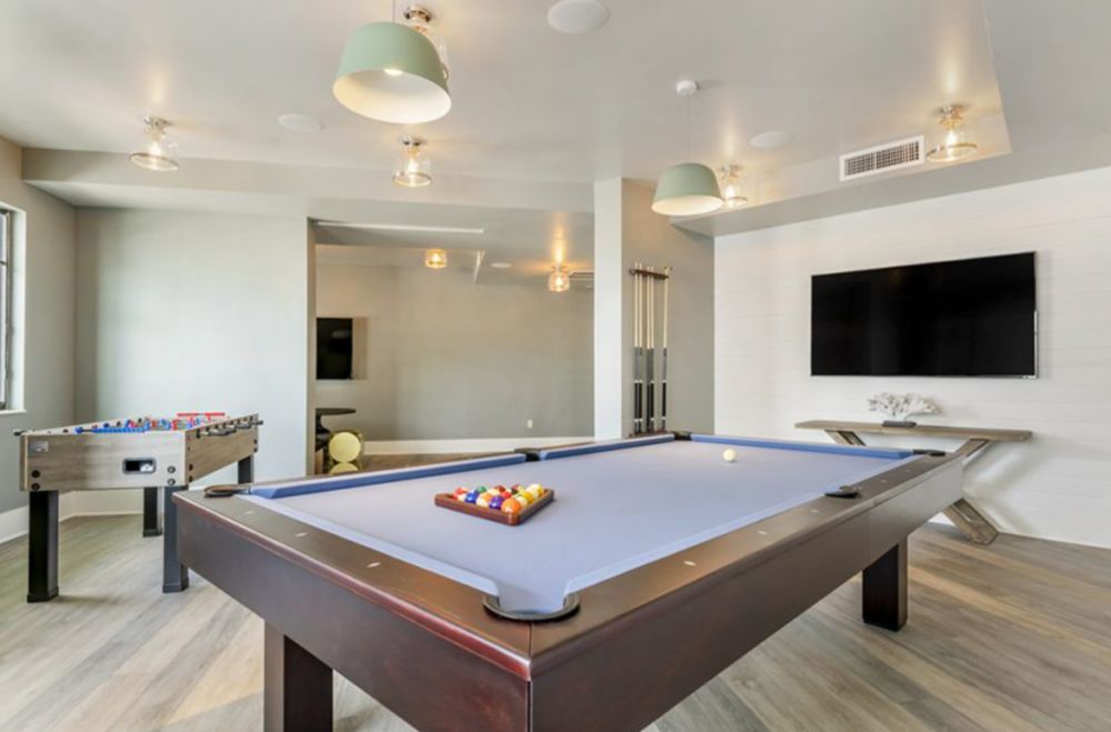A modern game room featuring a pool table and entertainment setup.