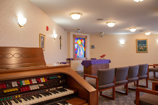A peaceful chapel interior featuring an organ and a colorful stained glass window.