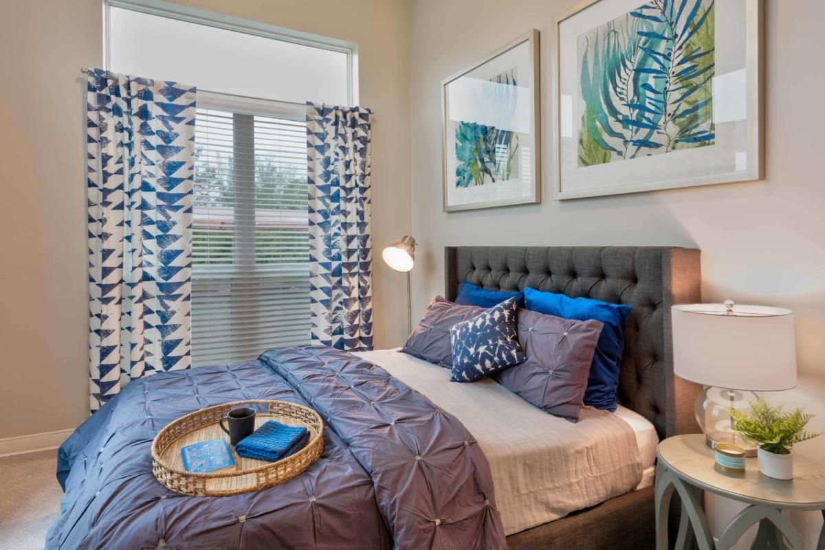 A modern and cozy bedroom featuring blue decor, patterned curtains, and stylish artwork.
