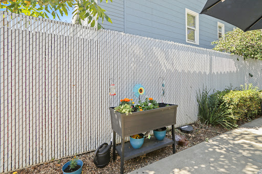 A well-maintained garden area featuring a planter box with colorful flowers, set against a wooden fence.
