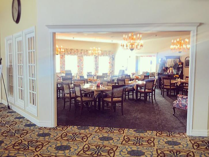 A spacious dining area with neatly arranged tables and chairs, bathed in natural light.