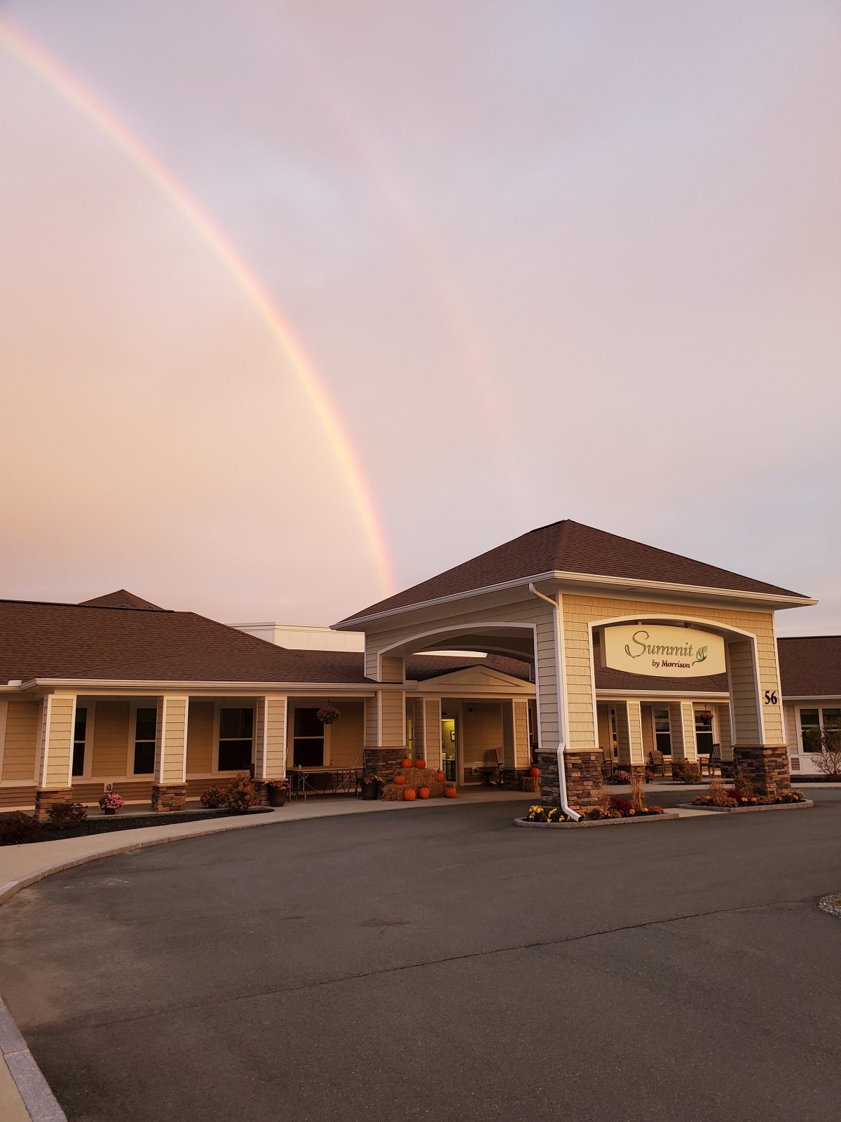 A beautiful rainbow appears over a building during sunset.