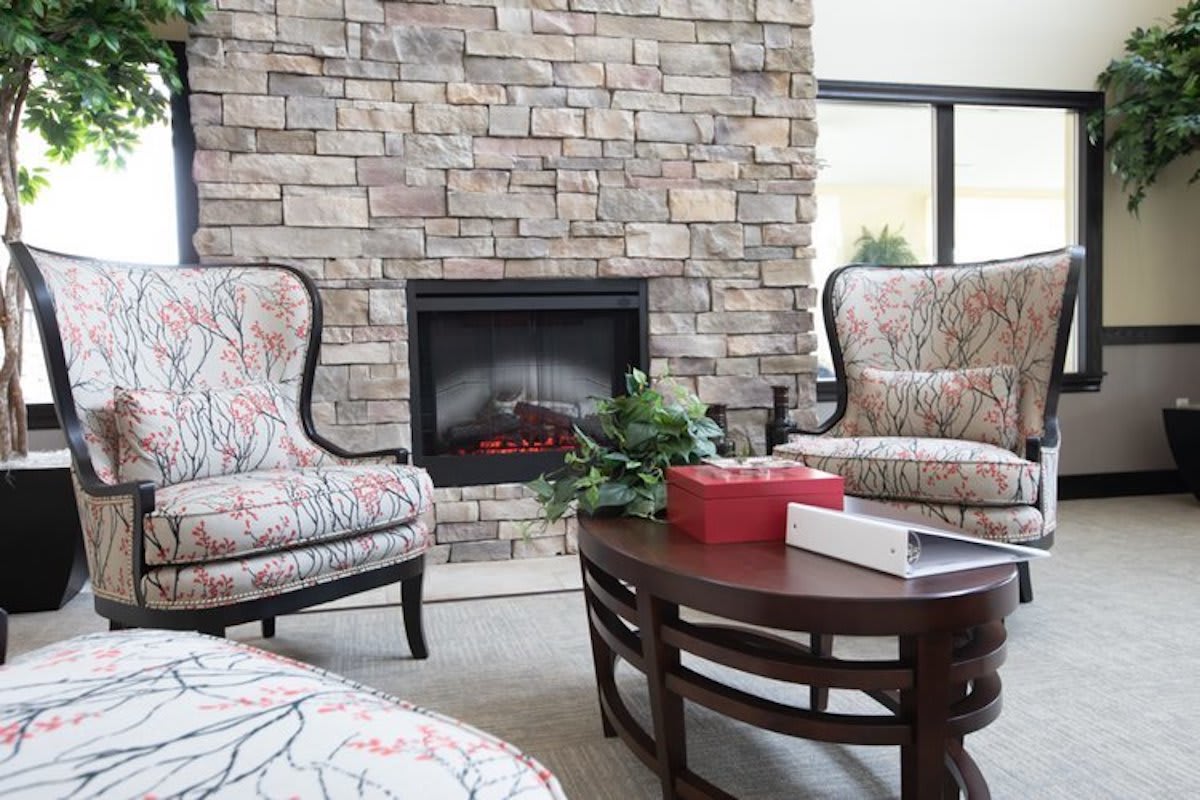 A cozy living room featuring a stone fireplace, decorated armchairs, and a wooden coffee table.