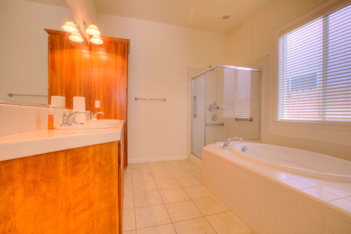 Spacious bathroom with a bathtub, shower, and wooden cabinetry.
