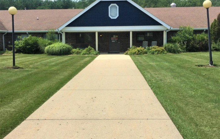A pathway leading to a building with landscaped lawns on both sides.