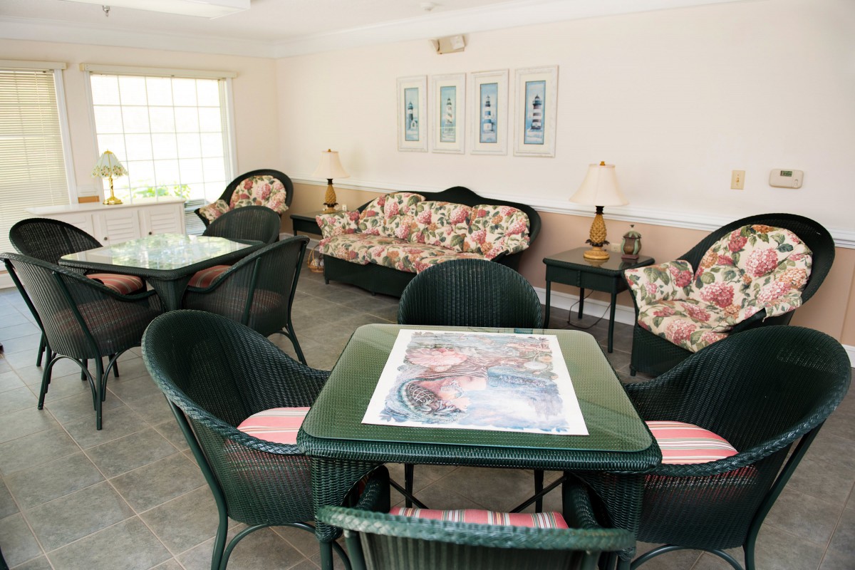 A cozy living room featuring floral sofas and wicker chairs around a small table.