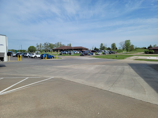A sunny day at a park with a busy parking lot and a pavilion in the background.