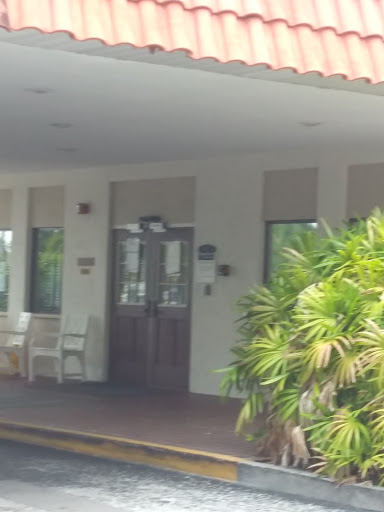 A welcoming entrance with a wooden door and outdoor seating, surrounded by greenery.