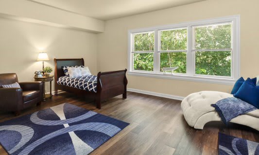A cozy bedroom with a single bed and a large window overlooking greenery.