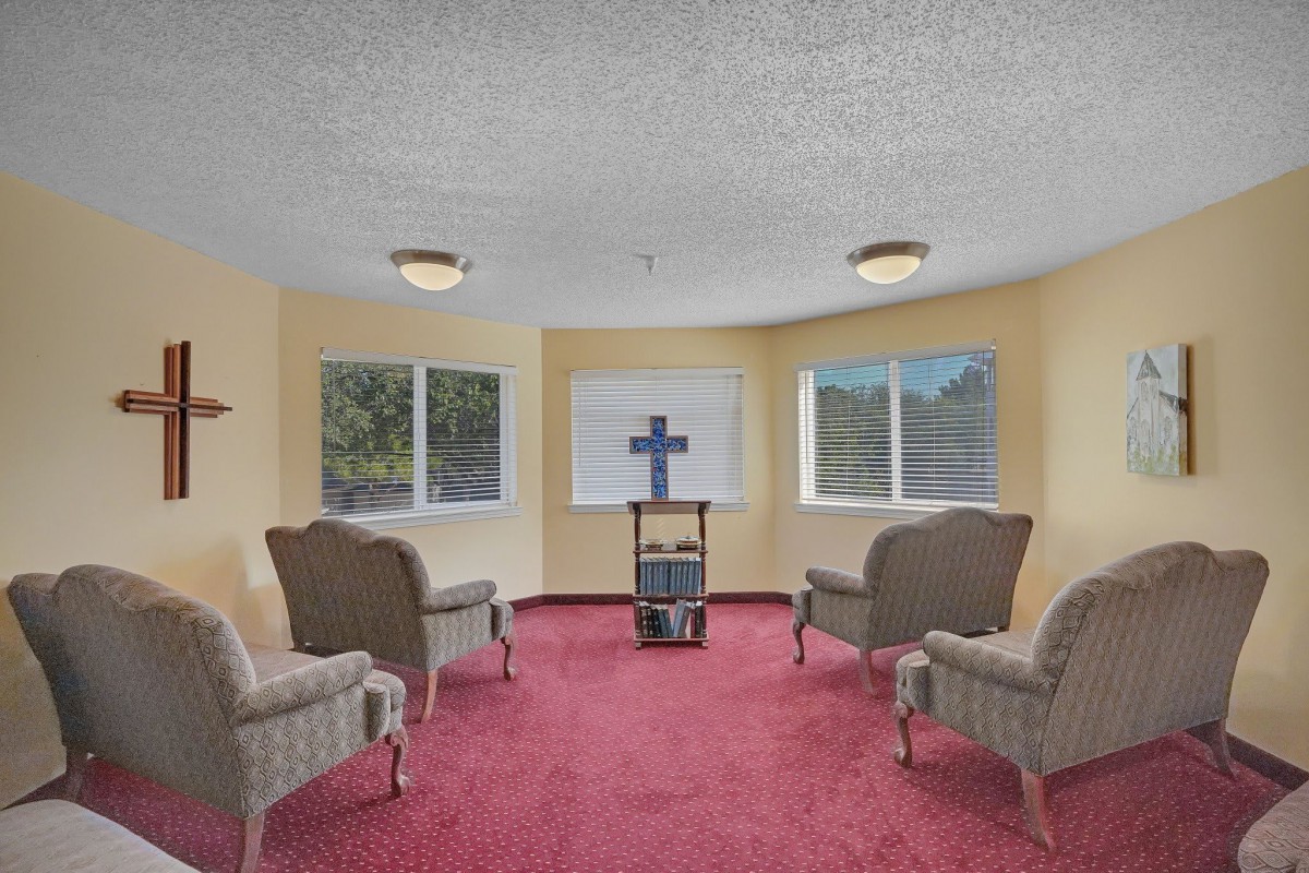A small chapel room with seating and a cross at the front.