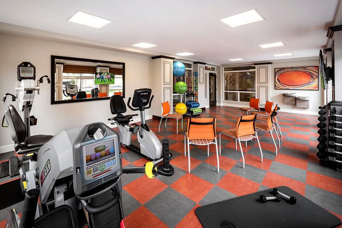 A brightly lit gym with exercise equipment and seating area.