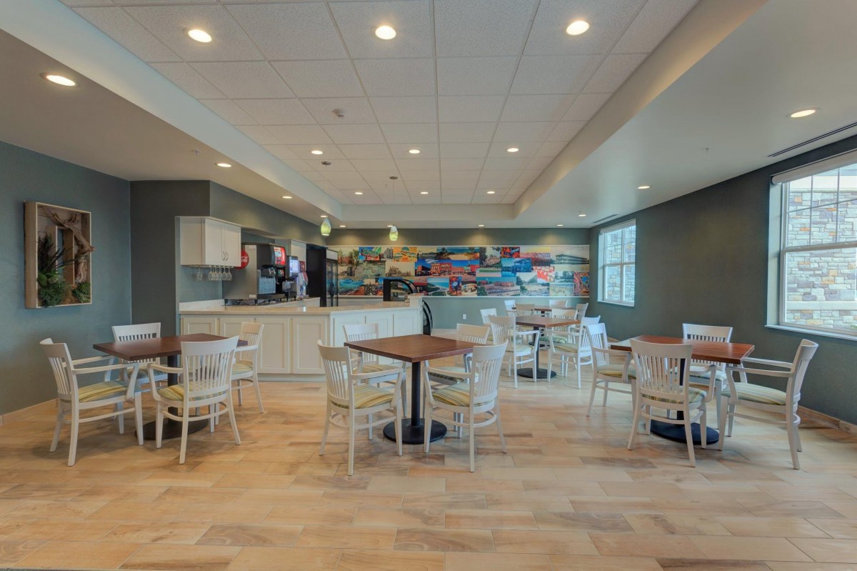 A modern cafe with multiple tables and chairs, featuring colorful wall art.