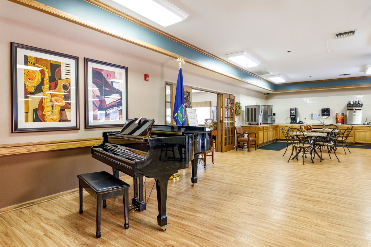 A well-lit lobby with a grand piano, surrounding furniture, and artwork on the walls.