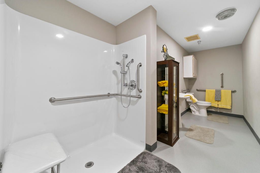 A modern and accessible bathroom featuring a walk-in shower with grab bars and neatly arranged towels.