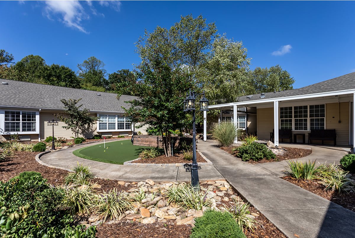 A picturesque garden with a charming house, surrounded by lush greenery and blue skies.